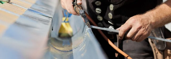 Person lötet Dachrinne